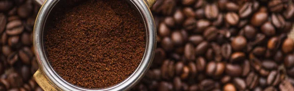 Top view of ground coffee in portafilter on coffee beans background, panoramic shot — Stock Photo