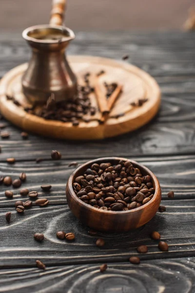 Selektiver Fokus der Kaffeebohnen in Schüssel und Cezve auf Holzoberfläche — Stockfoto