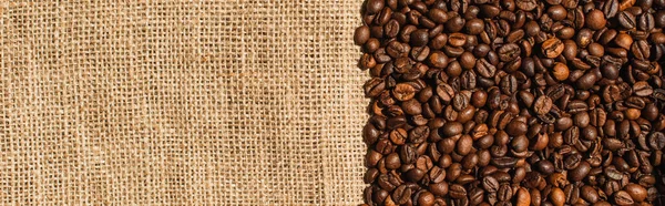 Top view of roasted coffee beans on sackcloth, panoramic shot — Stock Photo