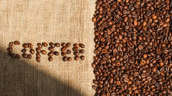 Ansicht von Kaffee-Schriftzug aus Bohnen im Sonnenlicht auf Sacktuch — Stockfoto