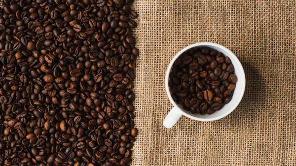 Vista dall'alto della tazza con chicchi di caffè e sacco sullo sfondo — Foto stock