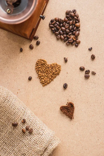 Top view of vintage coffee grinder near hearts and burlap on beige surface — Stock Photo