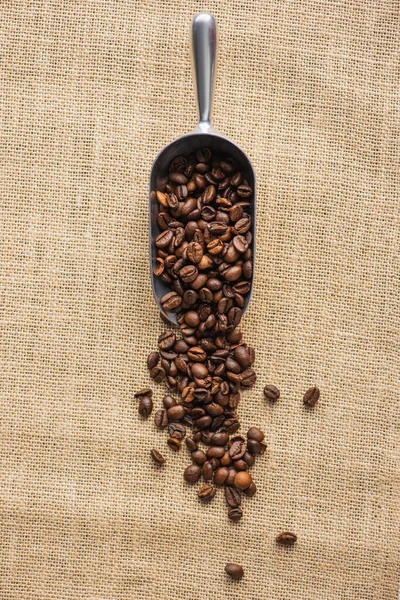 Vue du dessus de la cuillère en métal avec grains de café sur sac — Photo de stock