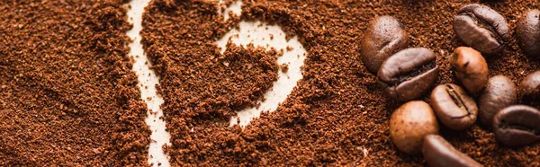 Close up view of heart drawn on ground coffee near beans, panoramic shot — Stock Photo