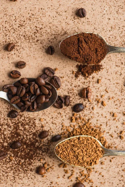 Vista dall'alto di terra, caffè istantaneo e fagioli in cucchiai su superficie beige — Foto stock