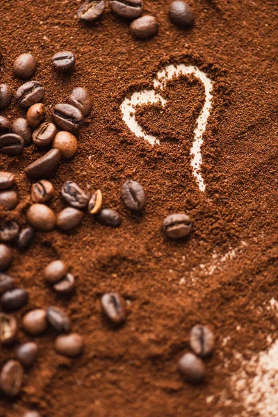 Selective focus of heart drawn on ground coffee near beans — Stock Photo