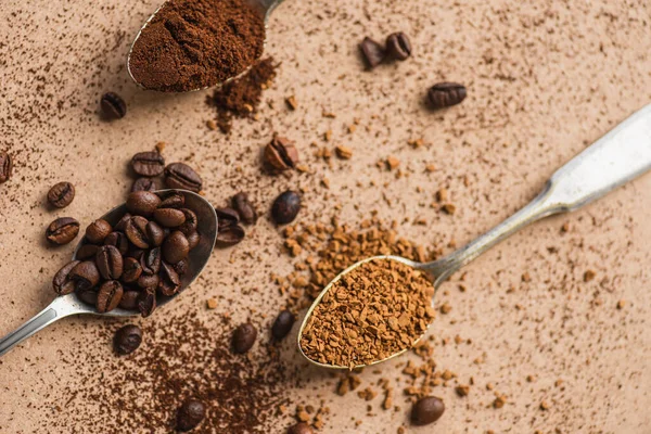 Vue de dessus du sol, café instantané et grains dans des cuillères sur la surface beige — Photo de stock