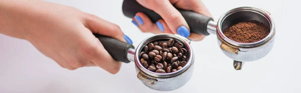 Vue recadrée de barista tenant des portafilters avec grains de café et café moulu sur fond blanc, vue panoramique — Photo de stock