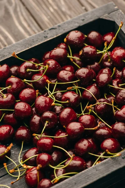 Cerises douces mûres humides en boîte sur une surface en bois — Photo de stock