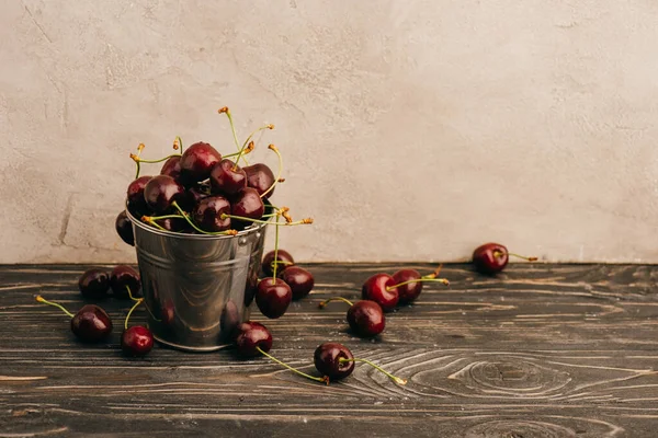Cerejas doces maduras molhadas em balde de metal na superfície de madeira — Fotografia de Stock