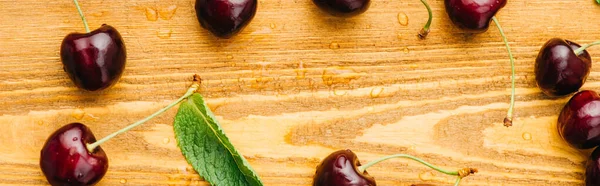 Vue de dessus des cerises douces mûres humides avec des feuilles vertes sur la surface en bois, vue panoramique — Photo de stock