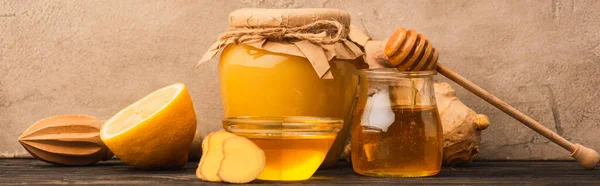 Sweet honey, ginger root and lemon on wooden surface near beige concrete wall, panoramic shot — Stock Photo