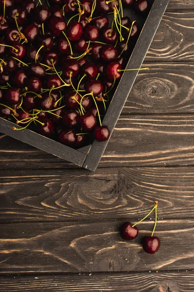 Верхний вид спелых сладких вишен в коробке на деревянной поверхности — стоковое фото