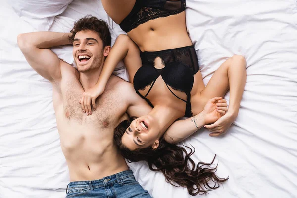 Vista superior do homem muscular e mulher em roupa interior deitada na cama — Fotografia de Stock