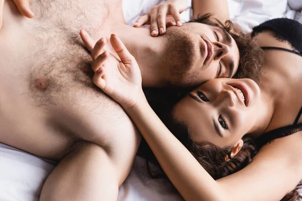 Мужчина и женщина без рубашки в лифчике отдыхают дома на кровати — стоковое фото