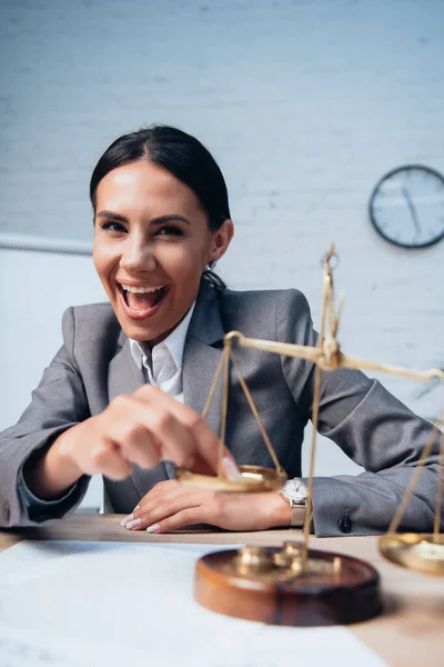 Selective focus of excited businesswoman in formal wear touching scales in office — Stock Photo