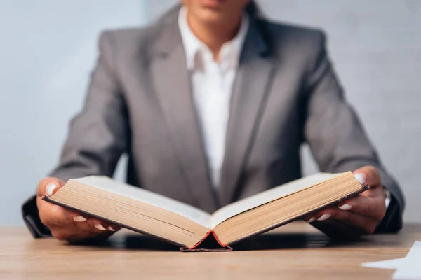 Foco seletivo do advogado no livro de leitura de terno no escritório — Fotografia de Stock