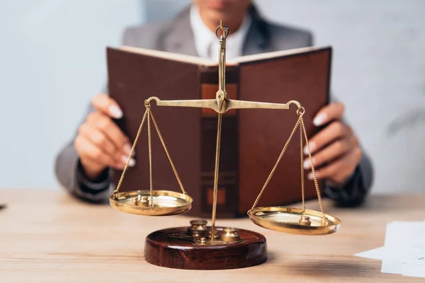 Selective focus of golden scales near lawyer with book — Stock Photo