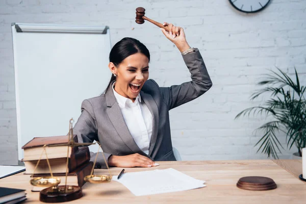 Selective focus of excited judge holding gavel near documents, scales and books — Stock Photo