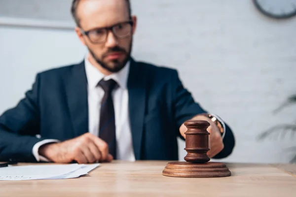 Selective focus of bearded judge holding gavel near papers on table — Stock Photo