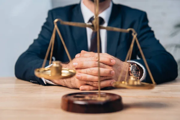 Selective focus of golden scales near lawyer in suit with clenched hands — Stock Photo