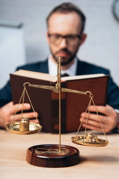 Селективный фокус золотых чешуек рядом с бородатым адвокатом, читающим книгу — стоковое фото
