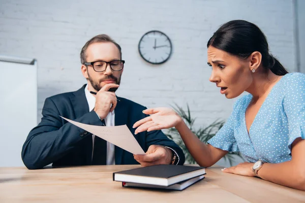 Selective focus of woman pointing with hand at document near bearded lawyer in glasses — Stock Photo