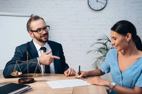 Orientation sélective de barbu avocat dans les lunettes pointant du doigt le client signant contrat d'assurance dans le bureau — Photo de stock