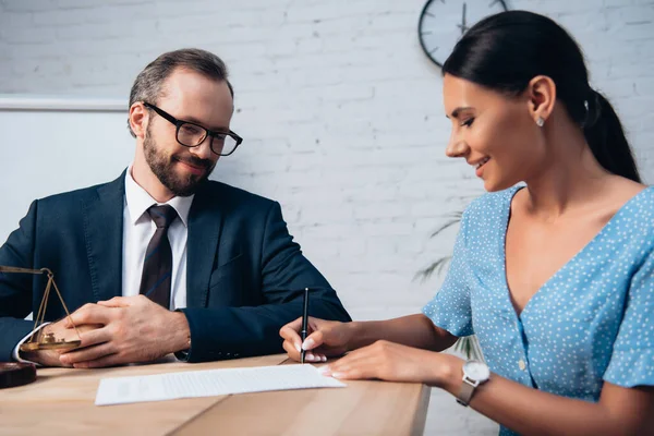 L'accent sélectif de barbu avocat dans les lunettes à la recherche d'une femme signant un contrat d'assurance en fonction — Photo de stock