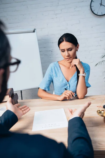 Selective focus of worried woman looking at insurance contract and biting lips near lawyer — Stock Photo