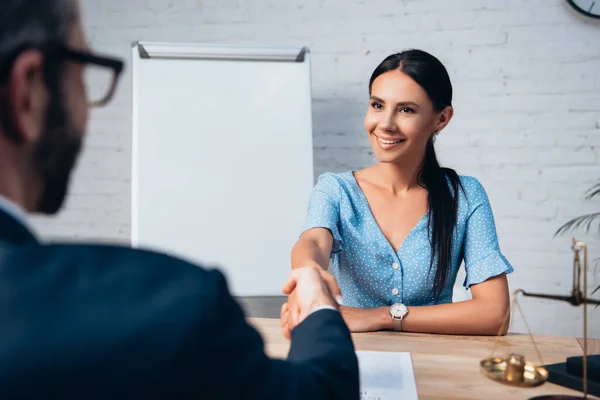 Selective focus of brunette client shaking hands with lawyer in office — Stock Photo