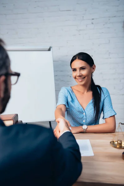 Foyer sélectif de la femme brune serrant la main avec un avocat au bureau — Photo de stock