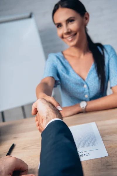Selective focus of brunette woman and lawyer shaking hands in office — Stock Photo