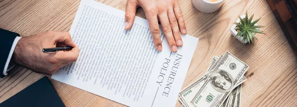 Panoramic shot of lawyer signing insurance policy agreement near plant and dollars — Stock Photo