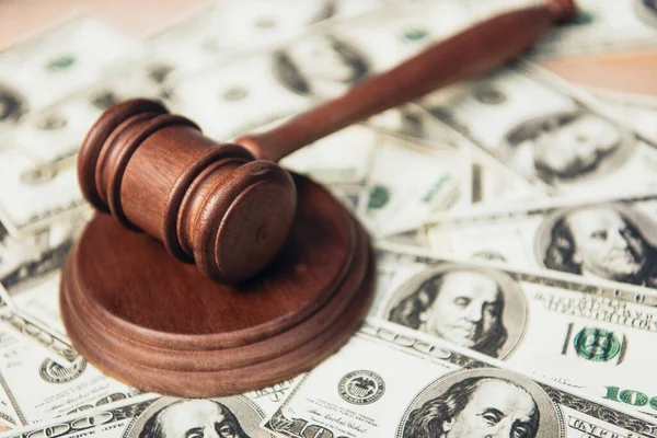 Selective focus of wooden gavel near dollar banknotes — Stock Photo