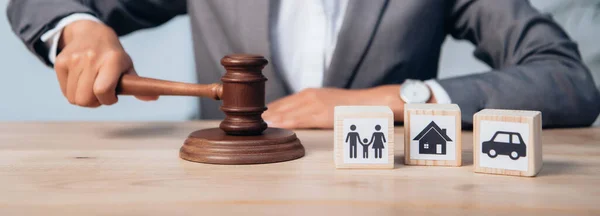 Horizontal image of judge holding gavel near wooden cubes with family, car and house — Stock Photo
