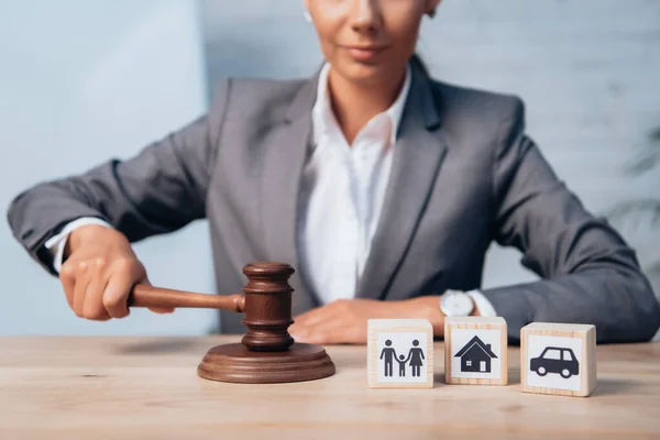 Cropped view of judge holding gavel near wooden cubes with family, car and house — Stock Photo