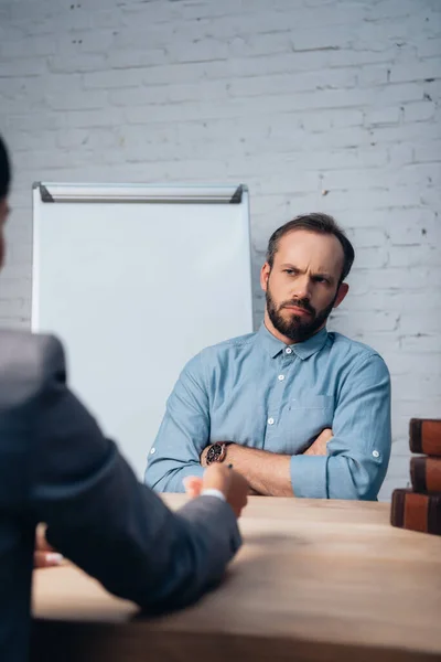 Selective focus of displeased client sitting with crossed arms near lawyer — Stock Photo