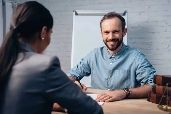 Selektiver Fokus eines bärtigen Mannes bei der Unterzeichnung eines Versicherungsvertrages in der Nähe eines brünetten Anwalts — Stockfoto