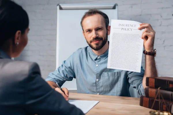 Selektiver Fokus des bärtigen Mannes mit Versicherungsvertrag und Stift in der Nähe brünetter Rechtsanwälte — Stockfoto