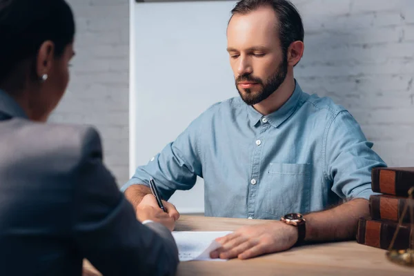 Orientation sélective du client barbu signature d'un accord d'assurance près de brunette avocat — Photo de stock