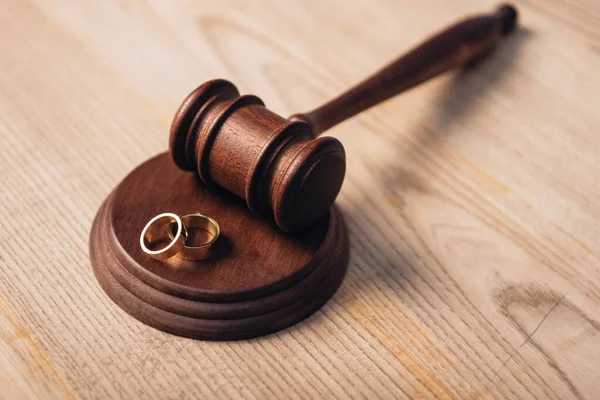 Enfoque selectivo de anillos de oro en martillo de madera, concepto de divorcio - foto de stock
