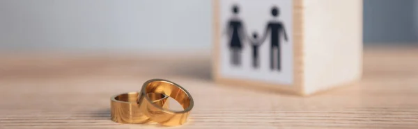 Panoramic shot of golden rings near wooden cube with family — Stock Photo