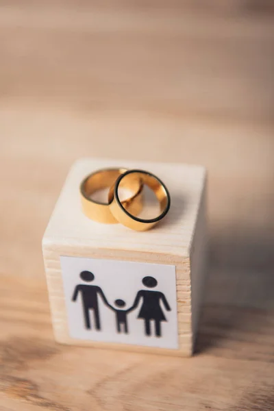 Selective focus of golden rings on wooden cube with family — Stock Photo