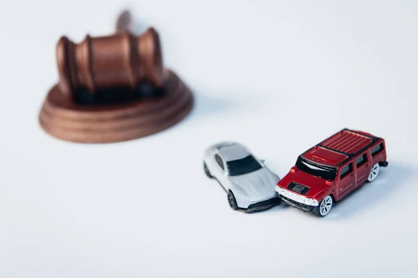 Foco seletivo de carros de brinquedo perto de martelo de madeira no branco, conceito de seguro — Fotografia de Stock