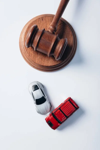 Vista superior de los coches de juguete cerca de martillo de madera en blanco, concepto de seguro - foto de stock