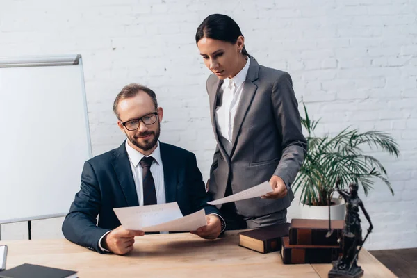 Bearded businessman and brunette businesswoman looking at documents in office — Stock Photo