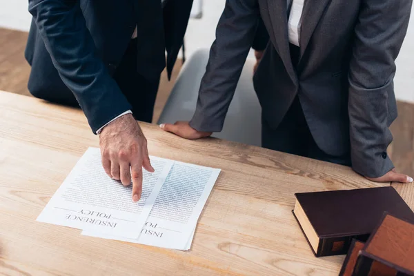 Cropped view of lawyer pointing with finger at documents with insurance policy lettering near businesswoman in office — Stock Photo