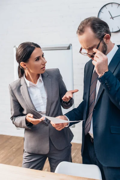 Geschäftsfrau schaut Anwalt an, der Versicherungsdokument im Amt hält — Stockfoto