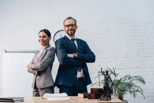 Lawyers in suits standing with crossed arms and looking at camera in office — Stock Photo